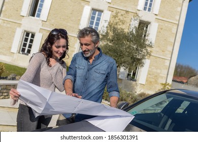 Portrait Of Happy Wealthy Middle Age Couple Studying A New Architecture  Project For Their House