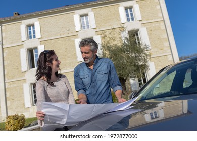 Portrait Of Happy Wealthy Middle Age Couple Studying A New Architecture  Project For Their House