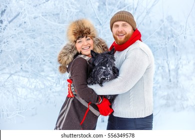 portrait of happy winter couple with pet small scottish terrier. Young man and woman in love with dog walking in the snowy forest - Powered by Shutterstock