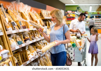 Portrait of happy woman choosing bread in bakery section in supermarket - Powered by Shutterstock