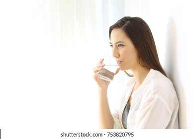 Portrait Of A Happy Woman Drinking Water From A Glass Isolated On White At Side