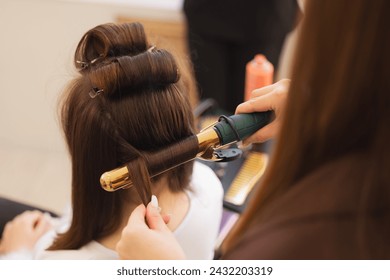 Portrait happy woman hairdresser stylist skillfully curling hair with golden iron in salon, hairstyle for wedding. - Powered by Shutterstock