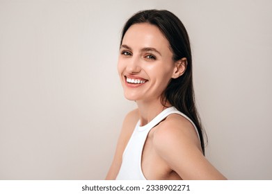 portrait of happy woman with healthy radiant skin and natural makeup looking at camera. model posing on copy space beige background. beauty procedure and skincare concept - Shutterstock ID 2338902271