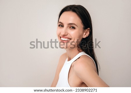 portrait of happy woman with healthy radiant skin and natural makeup looking at camera. model posing on copy space beige background. beauty procedure and skincare concept