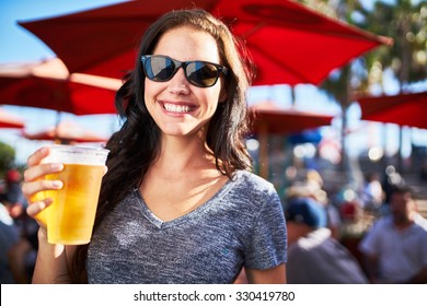 portrait of happy woman holding cup of beer outside on sunny day shot with selective focus
