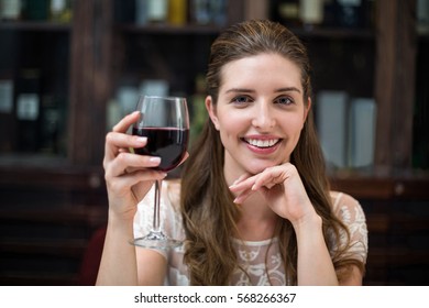 Portrait Of Happy Woman Holding Wine Glass At Restaurant