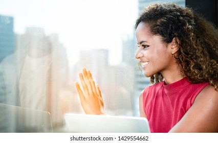 Portrait Of Happy Woman Looking Through The Window With Hands On The Glass And Say Hi.Young Lady Waiving And Saying Hello And Smiling,friendly Welcome Gesture Through Glass Window On High Building.