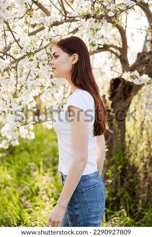 portrait of a happy woman with red hair in casual clothes enjoying the flowering of a fruit tree