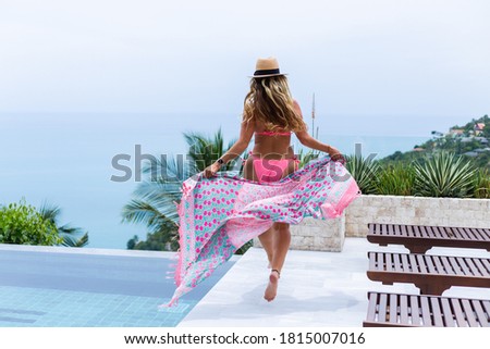 Portrait of happy woman running on vacation in bikini and beach sarong in hotel.