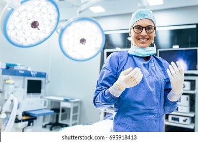 Portrait Of Happy Woman Surgeon Standing In Operating Room, Ready To Work On A Patient. Female Medical Worker In Surgical Uniform In Operation Theater.