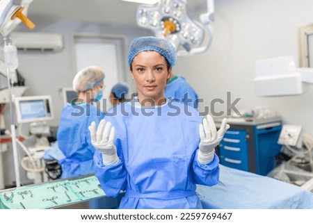 Portrait of happy woman surgeon standing in operating room, ready to work on a patient. Female medical worker in surgical uniform in operation theater.