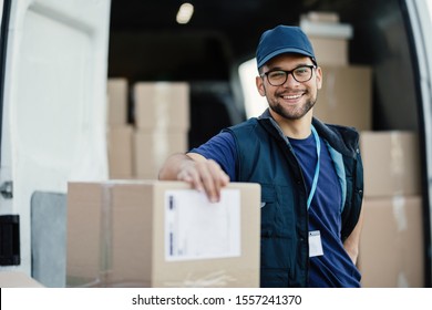 Portrait of happy worker unloading boxes from a delivery van and looking at camera. 