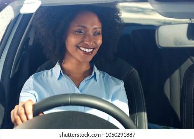 Portrait of happy young african american woman driving a car and smiling