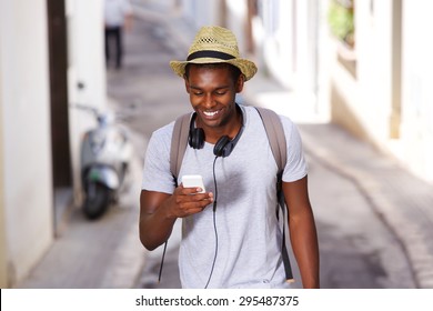 Portrait Of A Happy Young African American Man Walking In Town With Mobile Phone