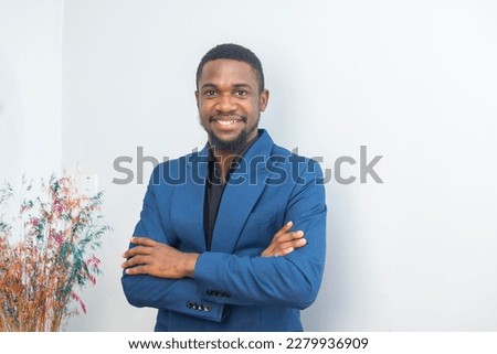 Portrait of happy young African businessman smiling with arms crossed