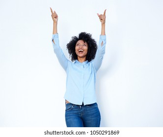 Portrait of happy young african lady pointing fingers up in excitement on white background