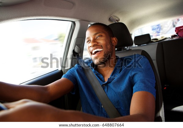 Portrait of happy young african man enjoying driving
a car