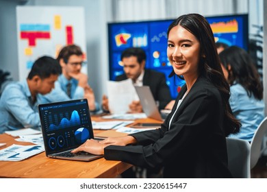 Portrait happy young asian businesswoman analyst looking at camera and her colleague analyzing data analysis in dynamic business strategy investment planning meeting  Habiliment