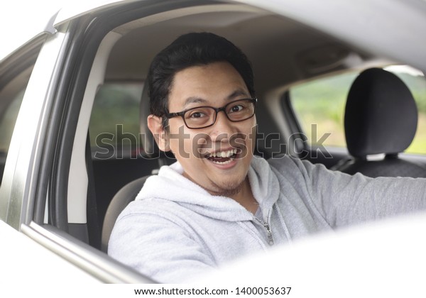 Portrait of happy young Asian driver in his car
smiling happily, lifestyle having fun leisure in vacation trip, car
ride sharing concept