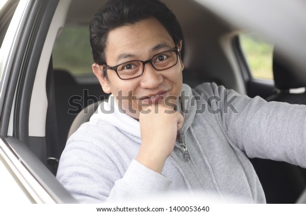 Portrait of happy young Asian driver in his car\
smiling happily, lifestyle having fun leisure in vacation trip, car\
ride sharing concept