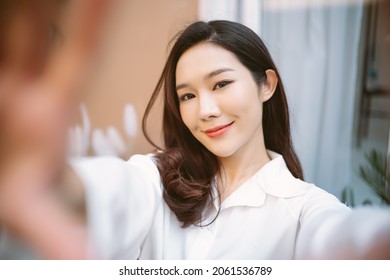 Portrait Of A Happy Young Asian Girl Holding Smartphone And Taking Picture Of Herself At Home.  Beauty And Healthy Woman. Happy Woman Lifestyle Concept.