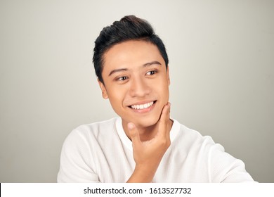 Portrait of happy young Asian man touching his chin