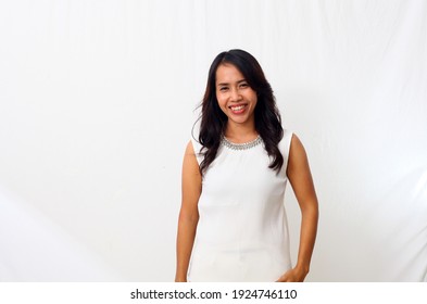 Portrait Of Happy Young Asian Woman Smiling Against White Wall