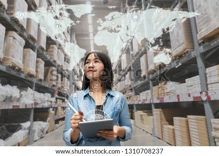 Portrait of happy young attractive asian entrepreneur woman looking at inventory in warehouse using smart tablet in management technology,  interconnected industry, asian small business sme concept.