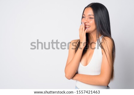 Portrait of happy young beautiful Asian woman laughing and covering mouth