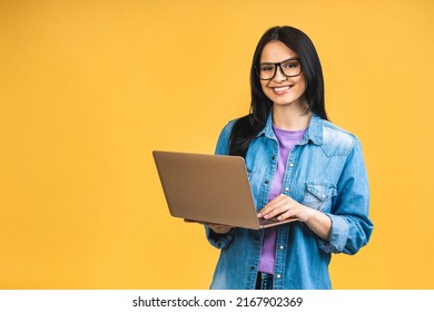 Portrait of happy young beautiful surprised woman with glasses standing with laptop isolated on yellow background. Space for text. - Powered by Shutterstock