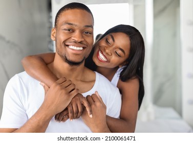 Portrait Of Happy Young Black Spouses Embracing In Bathroom Interior, Loving Young African American Couple Having Fun Together While Making Morning Beauty Self-Care Routine At Home, Closeup Shot
