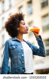 Portrait Happy Young Black Woman Drinking From Juice Bottle In City