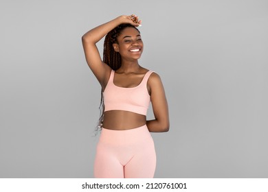 Portrait of happy young black woman in sports outfit posing and smiling on grey studio background. Fit millennial African American female being in great shape, leading active lifestyle - Powered by Shutterstock