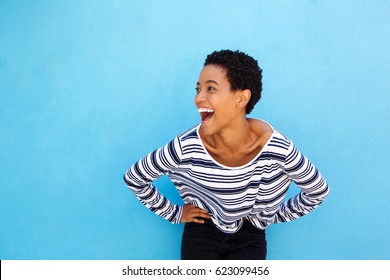 Portrait of happy young black woman laughing against blue background 