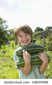 Portrait Of Happy Young Boy Holding Marrows In Community Garden