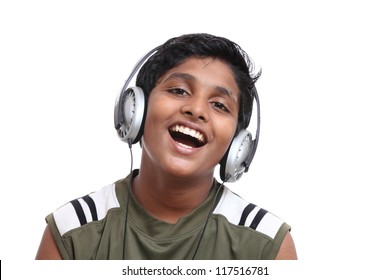 Portrait of a happy young boy listening to music on headphones against white background