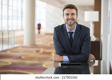 Portrait Of Happy Young Businessman Waiting In Hotel Lobby