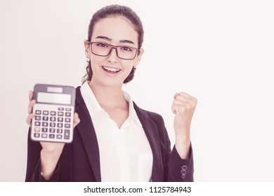 Portrait of happy young Caucasian businesswoman wearing glasses and suit holding calculator and showing winning gesture