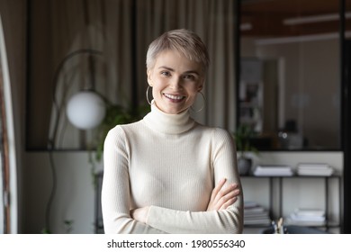 Portrait of happy young Caucasian confident businesswoman look at camera pose in modern office. Smiling female employee worker show leadership success at workplace. Employment, hr concept.