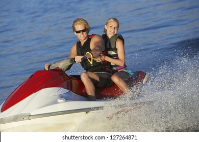 Portrait Of A Happy Young Caucasian Couple Riding Jet Ski On Lake