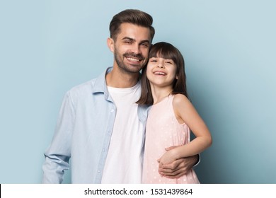 Portrait Of Happy Young Caucasian Dad And Cute Little Daughter Isolated On Blue Studio Background Hug Posing Together, Smiling Father And Preschool Girl Child Embrace Make Family Picture, Copy Space