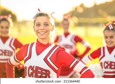 Portrait Of An Happy Young Cheerleader In Action Outdoors - Group Of Girlfriends During Cheerleading Sport Training At High School