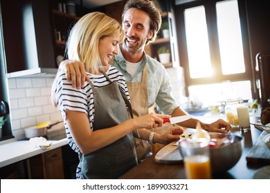 Portrait of happy young couple cooking together in the kitchen at home - Powered by Shutterstock