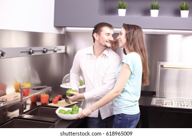 Portrait of happy young couple cooking together in the kitchen at home.