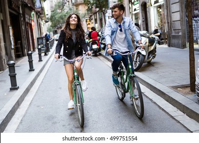 Portrait of happy young couple cycling in the city.