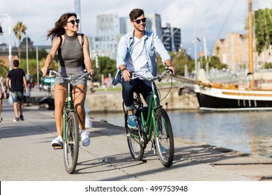 Portrait Of Happy Young Couple Cycling In The City.