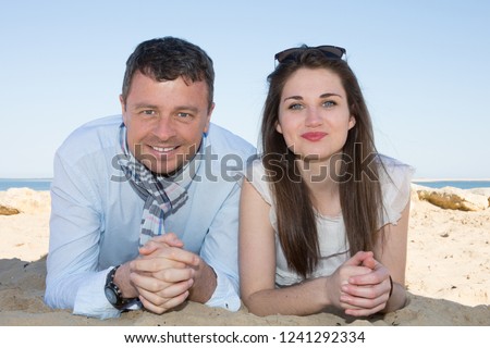 Portrait of happy young couple lying on beach dunes in summer day