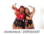 Portrait of happy young couple performing Dandiya Raas over white background