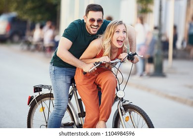 Portrait of happy young couple riding a bike in the city. - Shutterstock ID 1104984596