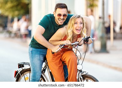 Portrait of happy young couple riding a bike in the city. - Shutterstock ID 651786472